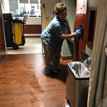 A woman wipes down a cabinet in a patient room in the hospital