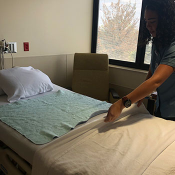 A woman makes a bed in a patient room at Tristar Hendersonville