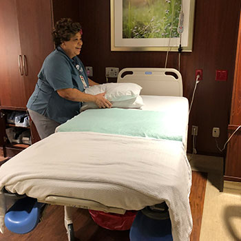 A woman holds two pillows in a patient room