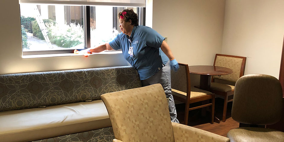 a nurse wiping down surfaces in a hospital commmon area