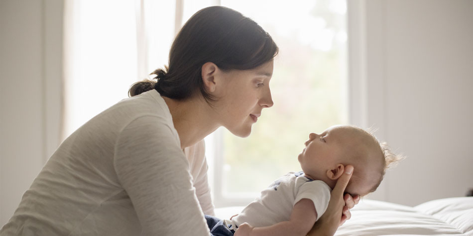 a parent holding their newborn baby as they look into each others eyes