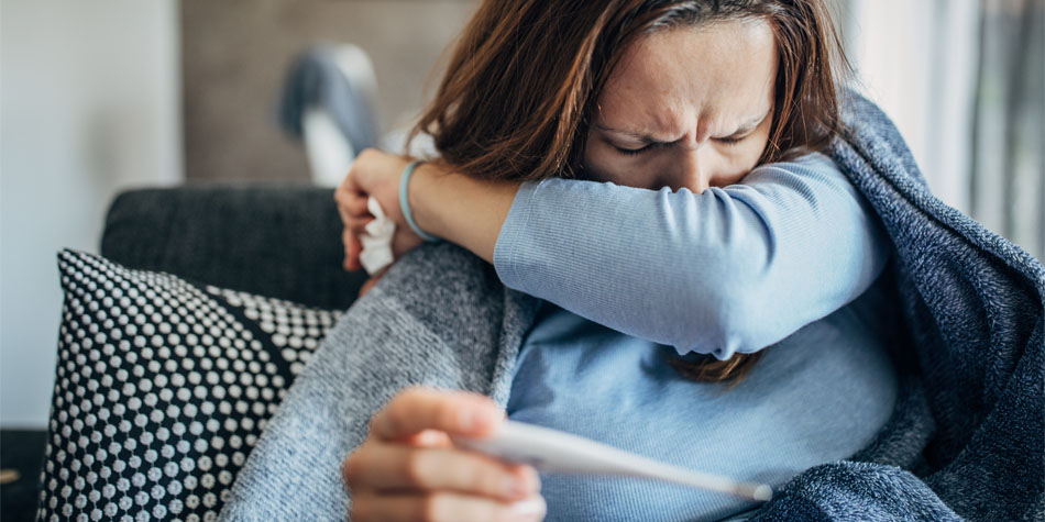 a person holding a thermometer while the sneeze intensely