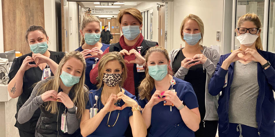 a team of nurses standing in a hospital hallway while holding their hands in the shape of a heart