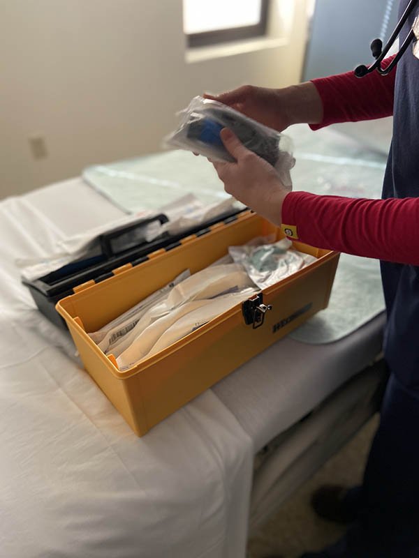 Lindsey, a respiratory therapist, unpacks materials for intubation from a supply box